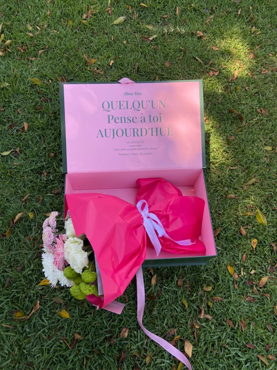 Bouquet enveloppé de papier fuchsia dans la boîte signature Alma Viva